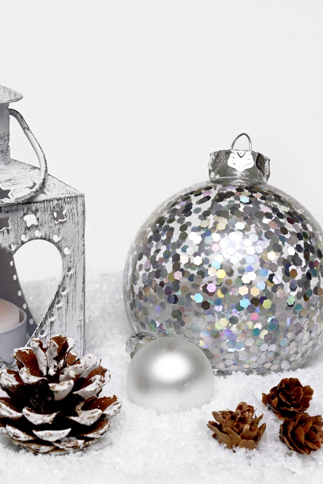 Фонарик и елочный шар с шишками на снегу