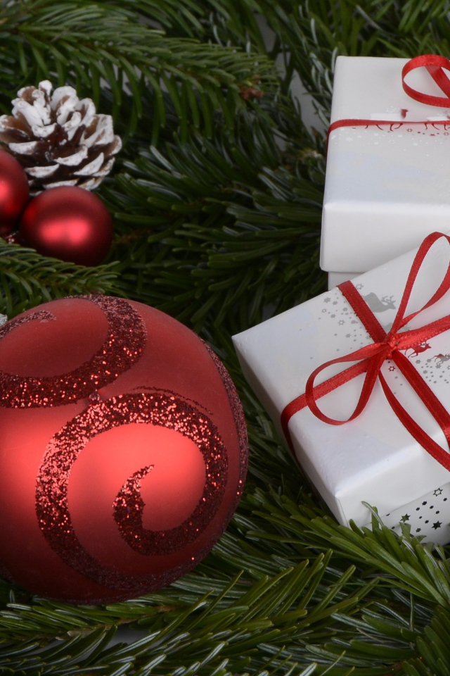 Два белых подарка, красный шар и еловая ветка на новый год 