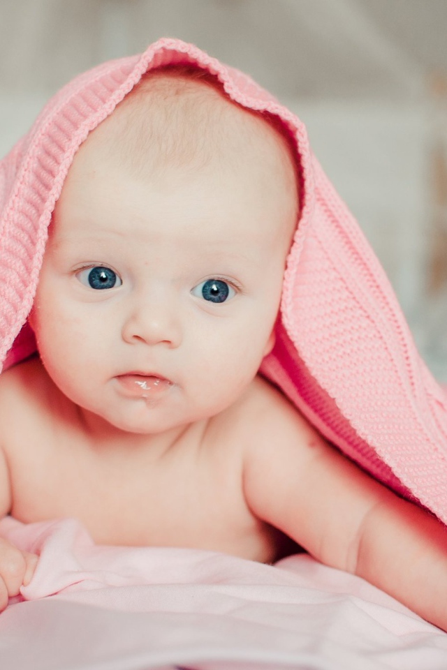 Грудной ребенок лежит под розовым пледом