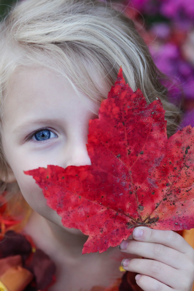 Маленькая девочка закрывает лицо листом