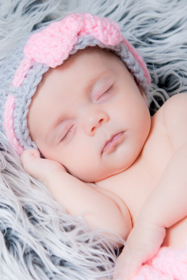 Грудной ребенок спит на меховом одеяле 