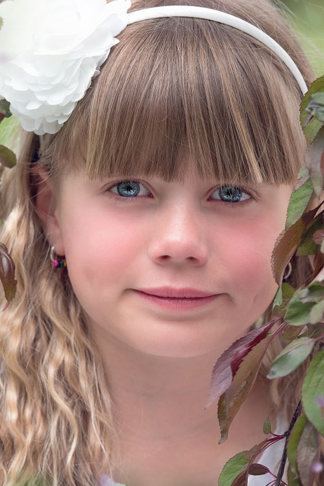 Красивая голубоглазая девочка с белым цветком на голове 