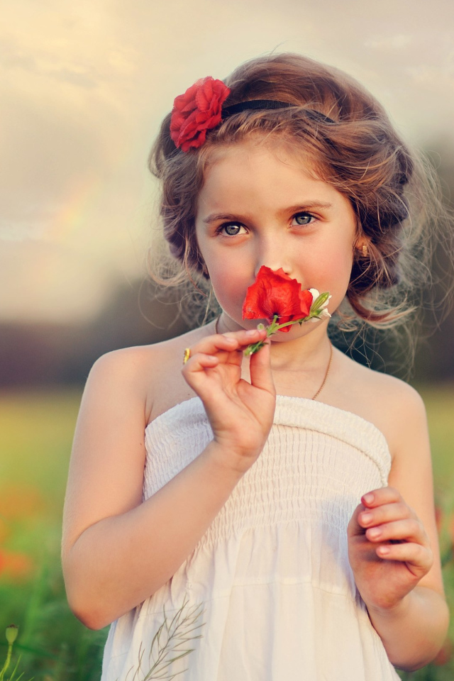 Красивая девочка в белом платье с цветком красного мака в руке 