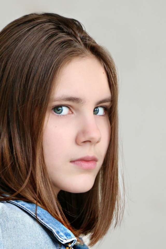 Красивая зеленоглазая девочка на сером фоне