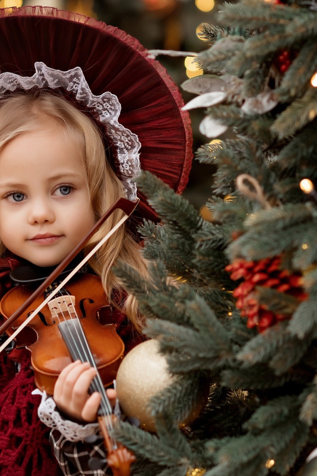 Красивая маленькая девочка со скрипкой у ели