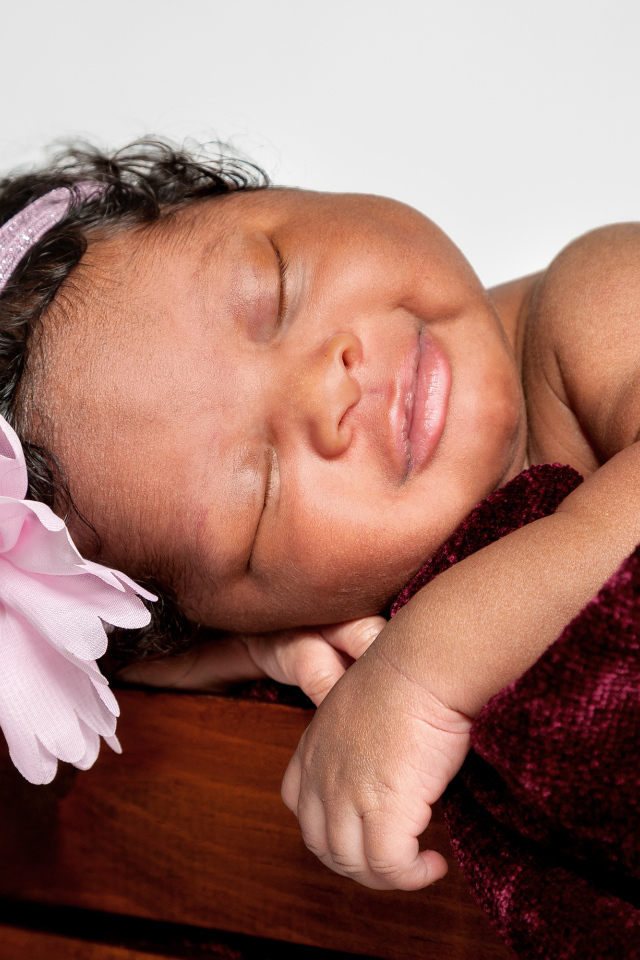 Темнокожая маленькая девочка с розовым цветком на голове 