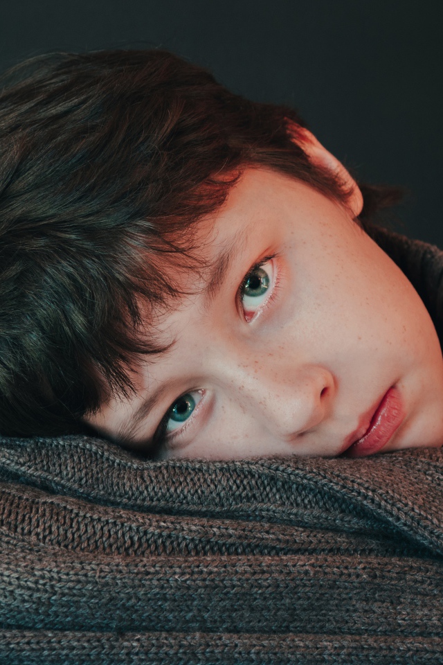 Мальчик в теплом свитере на сером фоне 