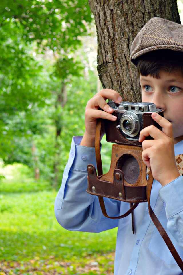 Мальчик с фотоаппаратом в руках в парке