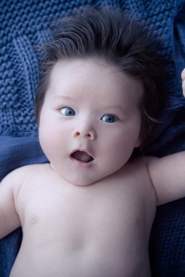 Мальчик с густыми волосами на синем покрывале 