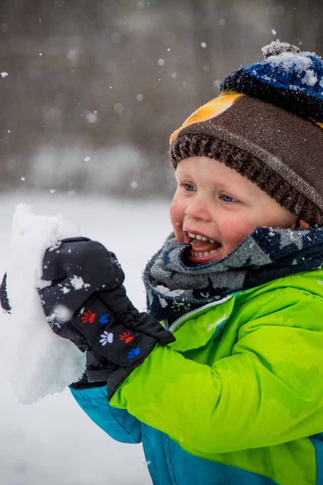 Веселый маленький мальчик со снегом в руках 