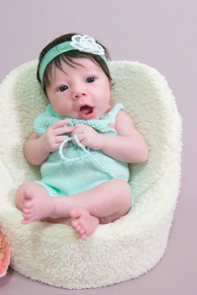 Милая малышка в кресле с букетом цветов