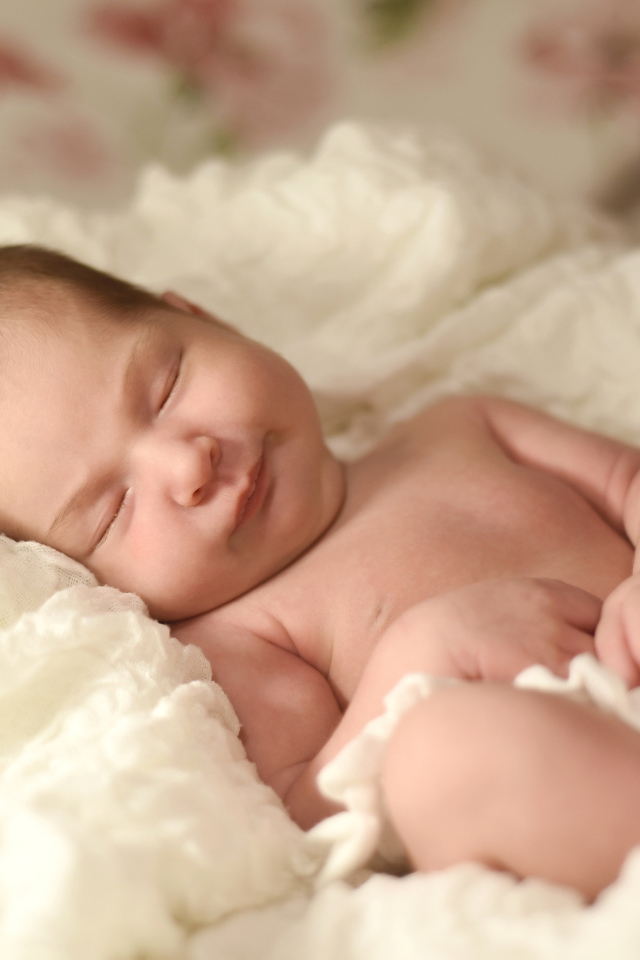 Милый грудной ребенок спит на белом покрывале 