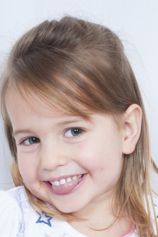 Милая улыбающаяся девочка с высунутым языком