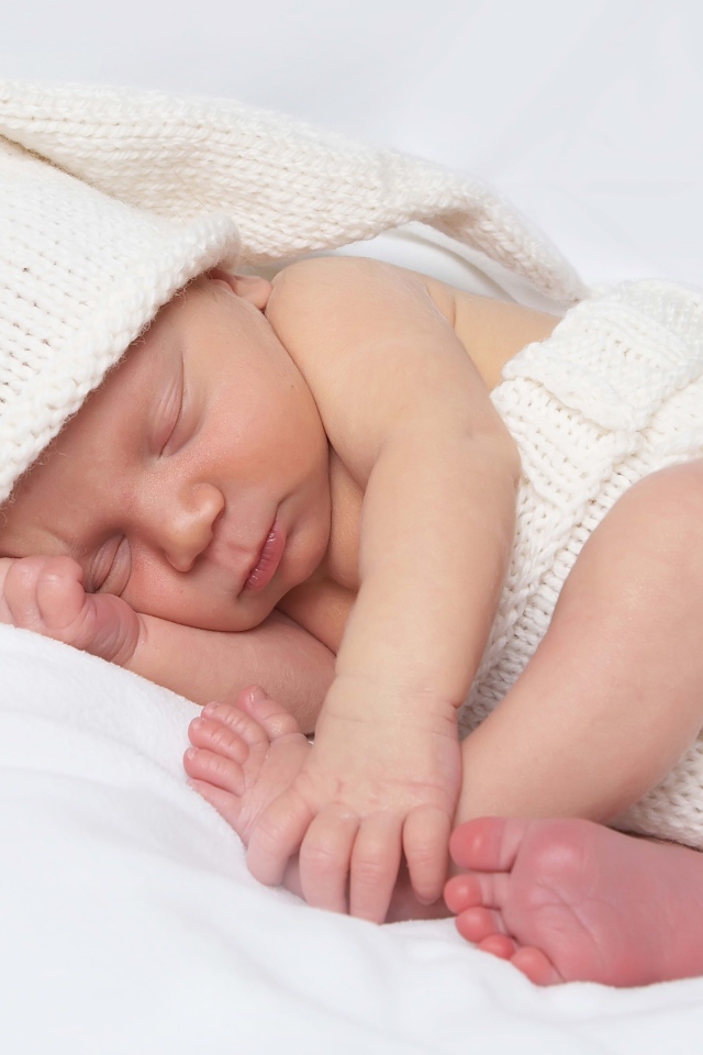 Нежный новорожденный ребенок в белом костюме