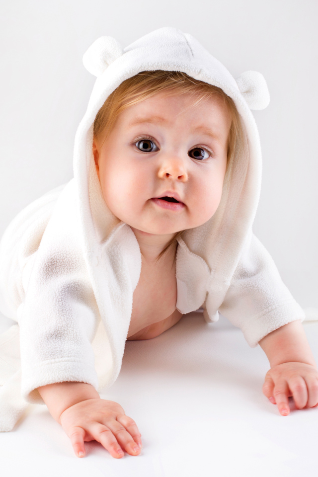 Забавный малыш ползает в белом наряде 