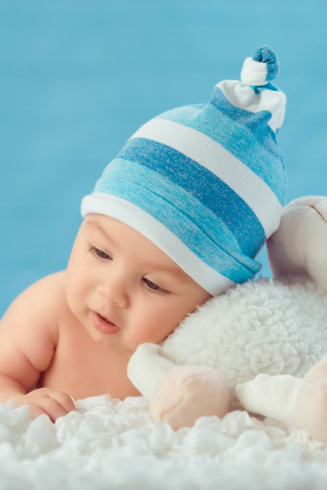 Забавный малыш с игрушкой на голубом фоне