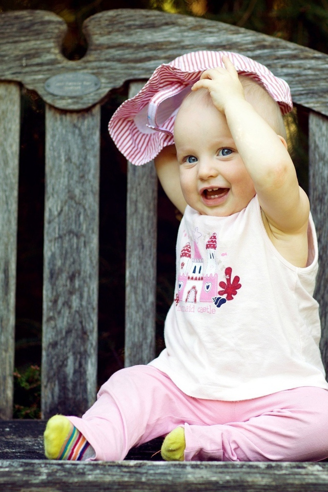 Смешной маленький ребенок сидит на лавке