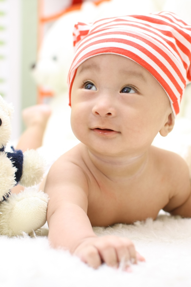 Маленький мальчик азиат на кровати с игрушкой