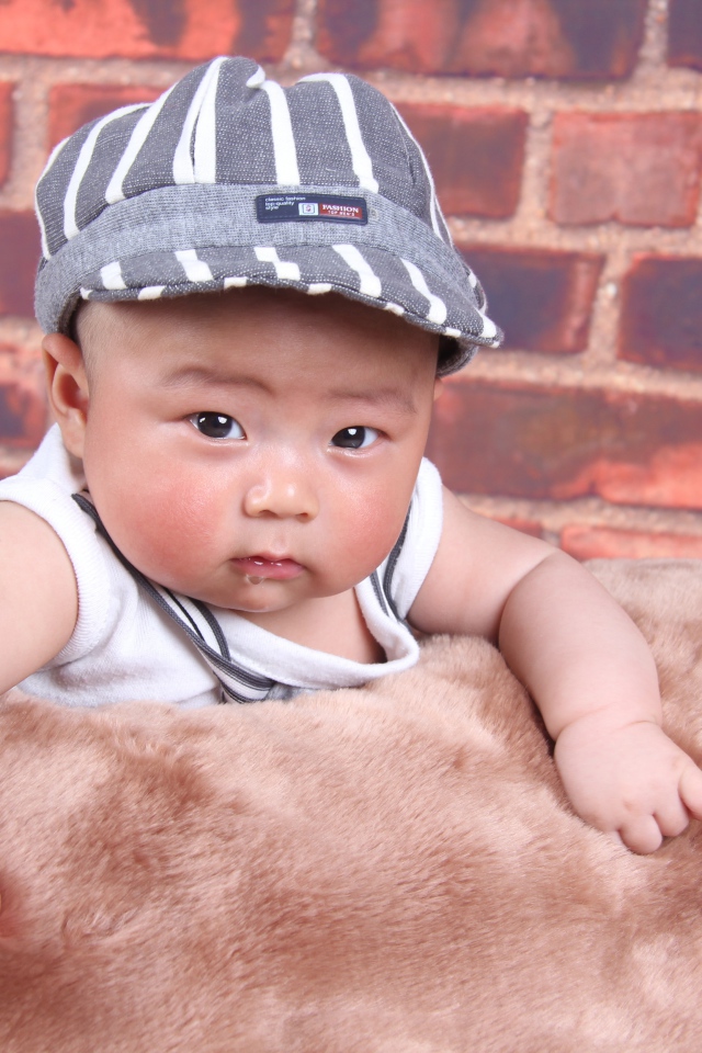 Маленький азиатский ребенок на фоне стены