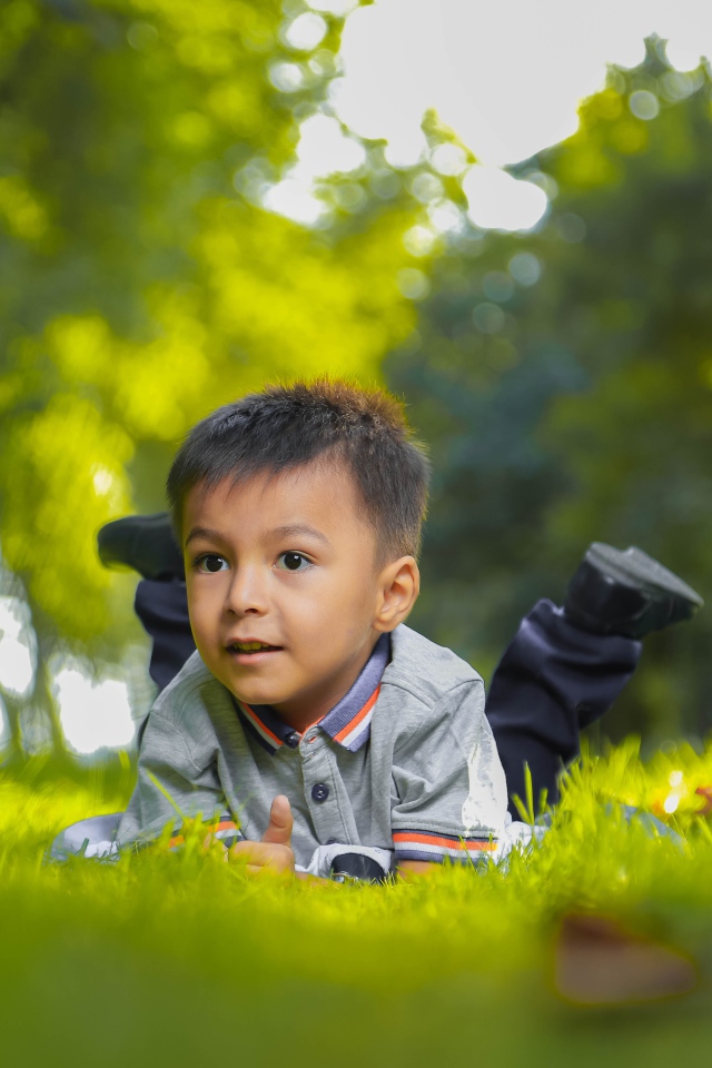 Маленький мальчик лежит на зеленой траве 