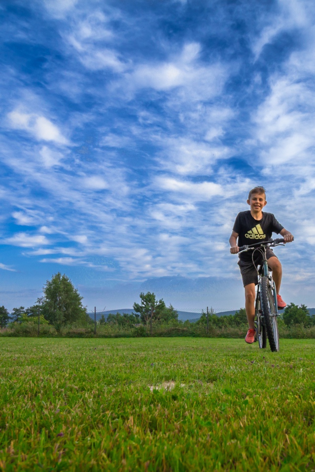 Маленький мальчик катается на велосипеде по полю 
