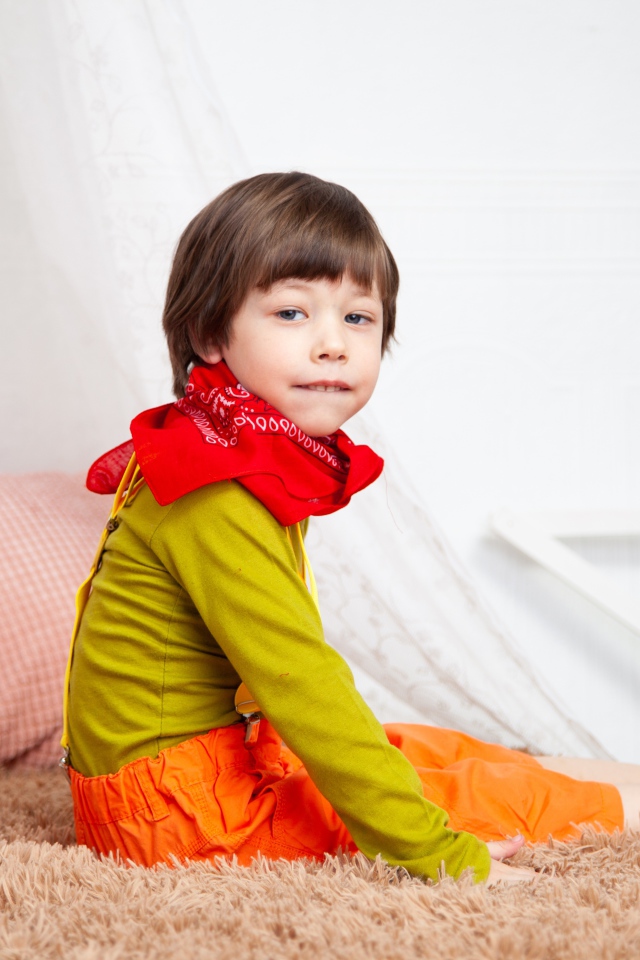 Маленький мальчик сидит на кровати