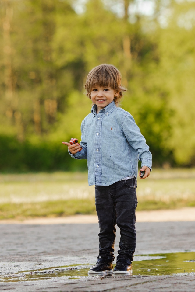Маленький мальчик стоит в луже на дороге 