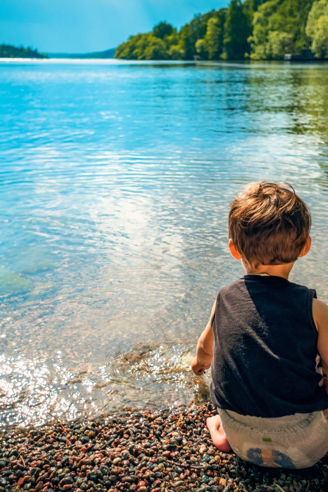 Маленький мальчик кидает камни в воду
