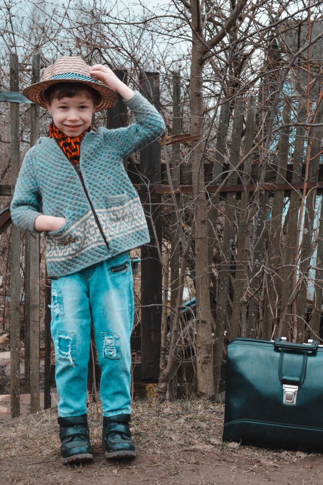 Маленький мальчик с чемоданом у забора