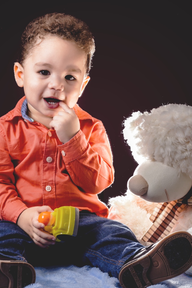 Маленький мальчик с игрушечным медведем на черном фоне