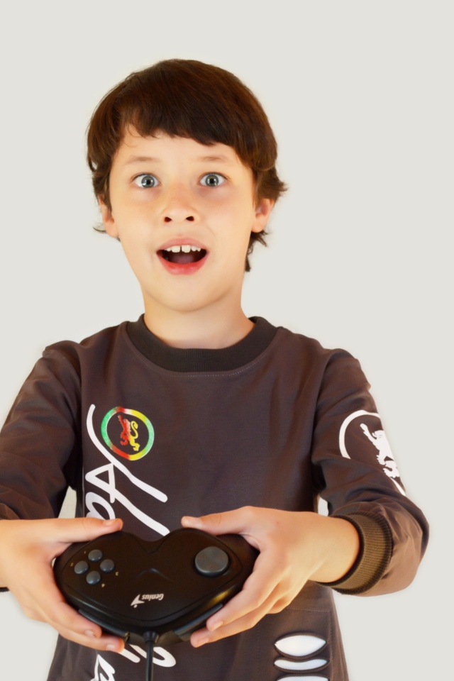 Маленький мальчик с приставкой на сером фоне 