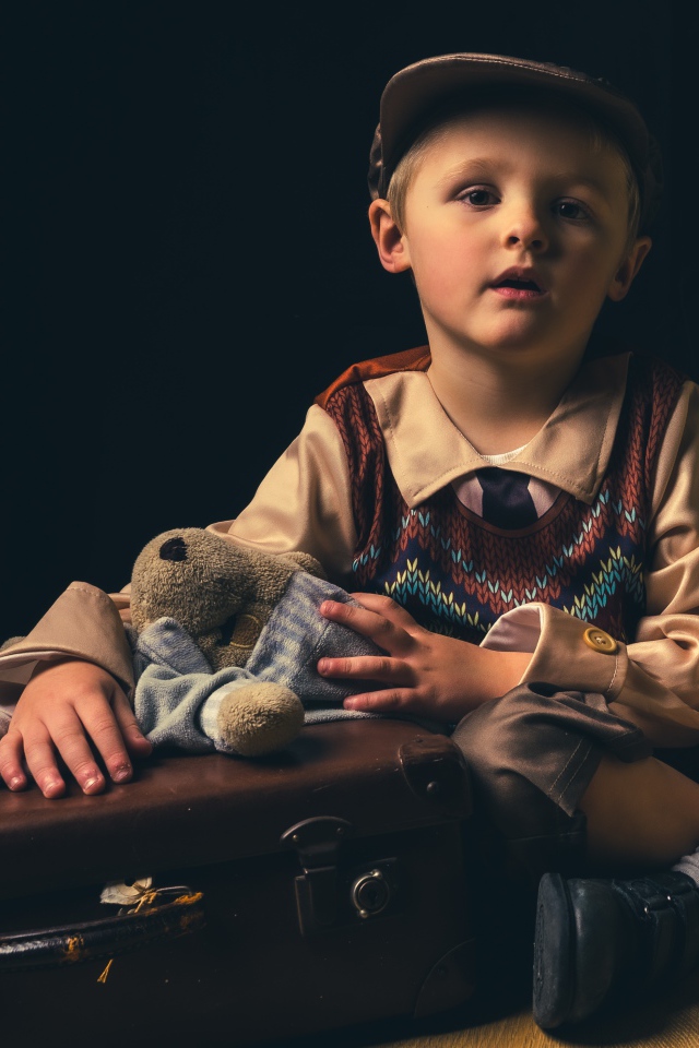 Маленький мальчик с чемоданом и игрушкой