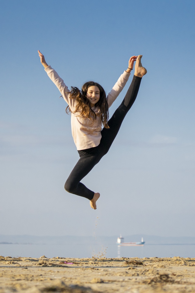 Маленькая девочка гимнастка на песке