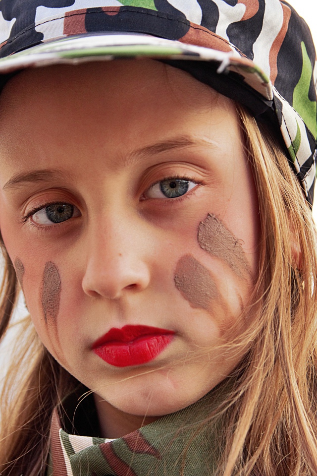 Маленькая девочка в кепке с грязью на лице