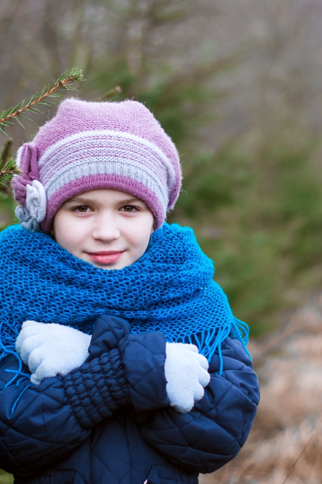 Маленькая девочка в теплой одежде у ели
