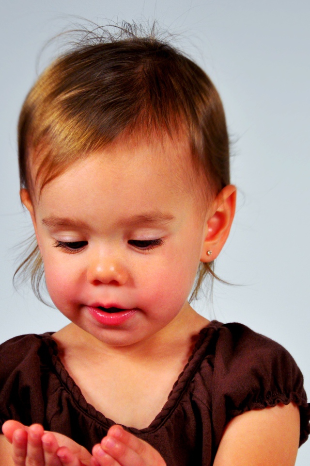 Маленькая девочка смотрит на руки на сером 