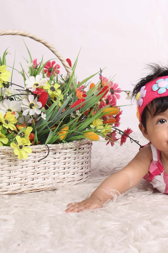 Маленькая девочка рядом с корзиной цветов 