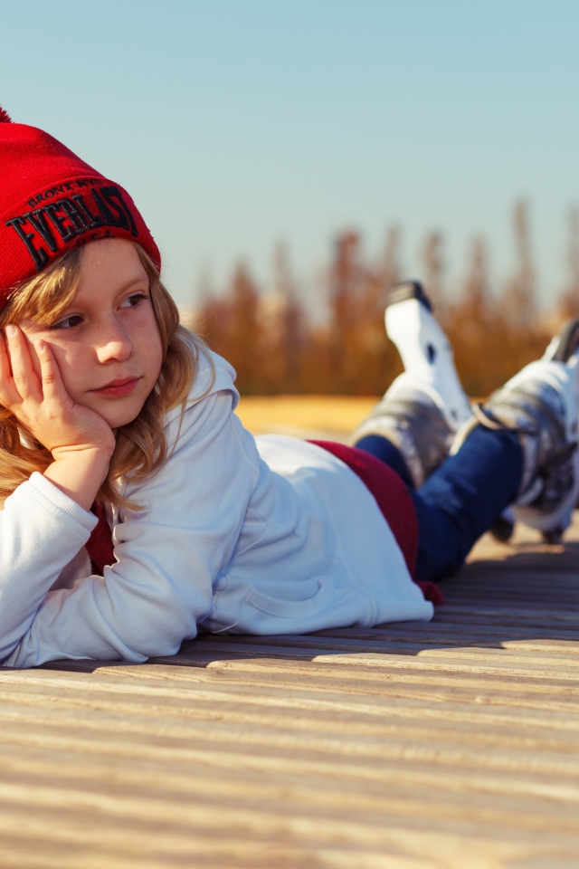 Маленькая девочка на роликах лежит на мосту