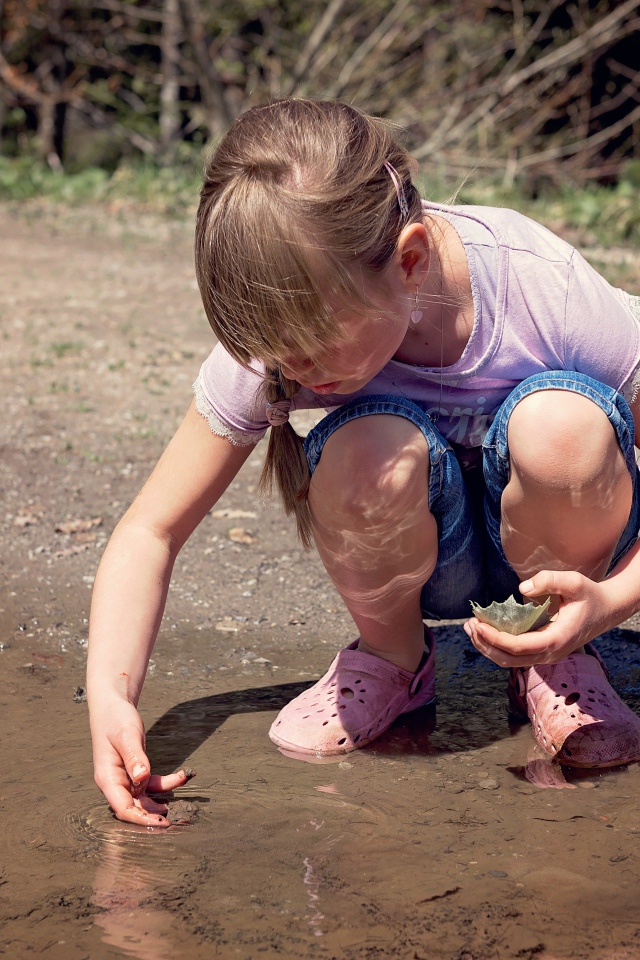 Маленькая девочка играет в луже 