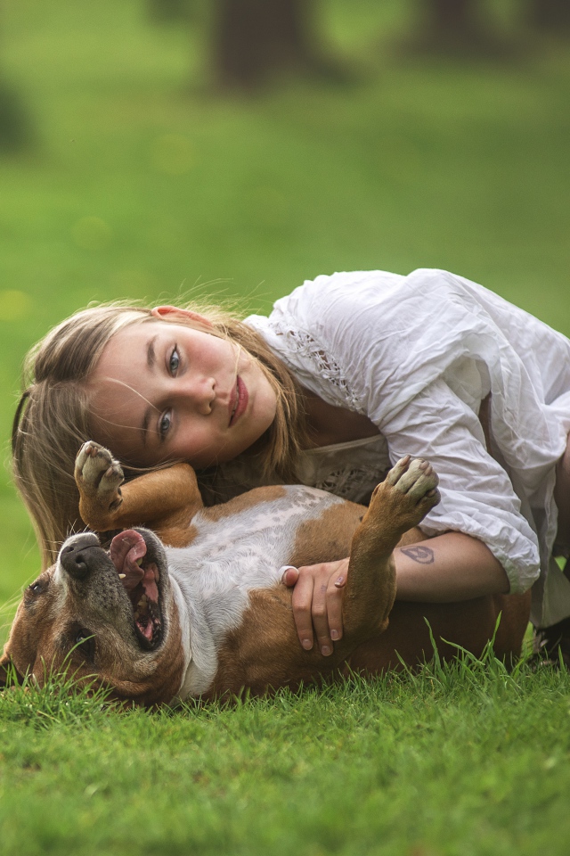Маленькая девочка играет с собакой на траве летом