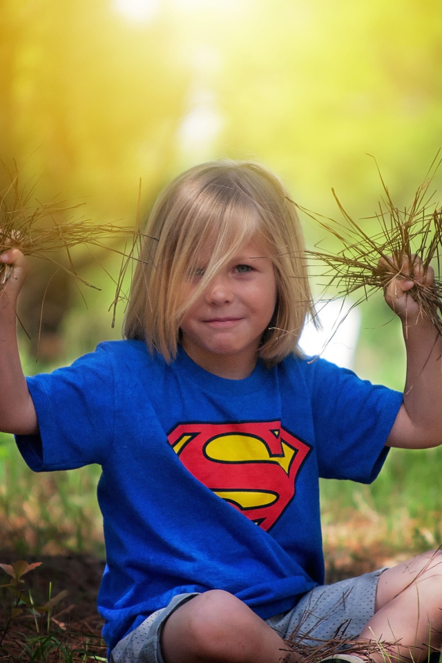 Маленькая девочка сидит на земле с травой