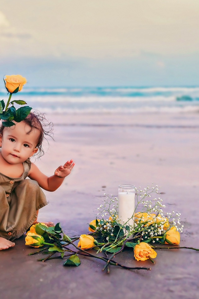 Маленькая девочка сидит на песке с розами 