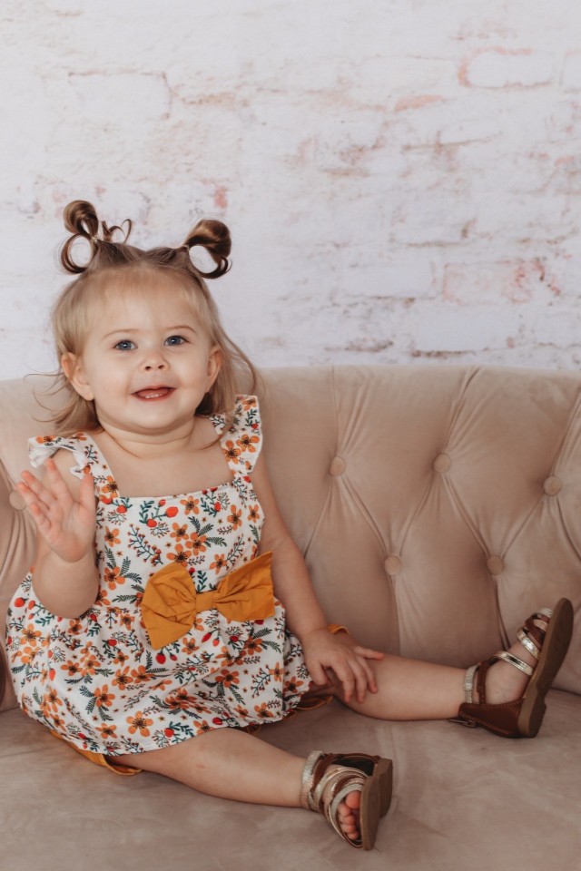 Маленькая девочка сидит на диване у стены