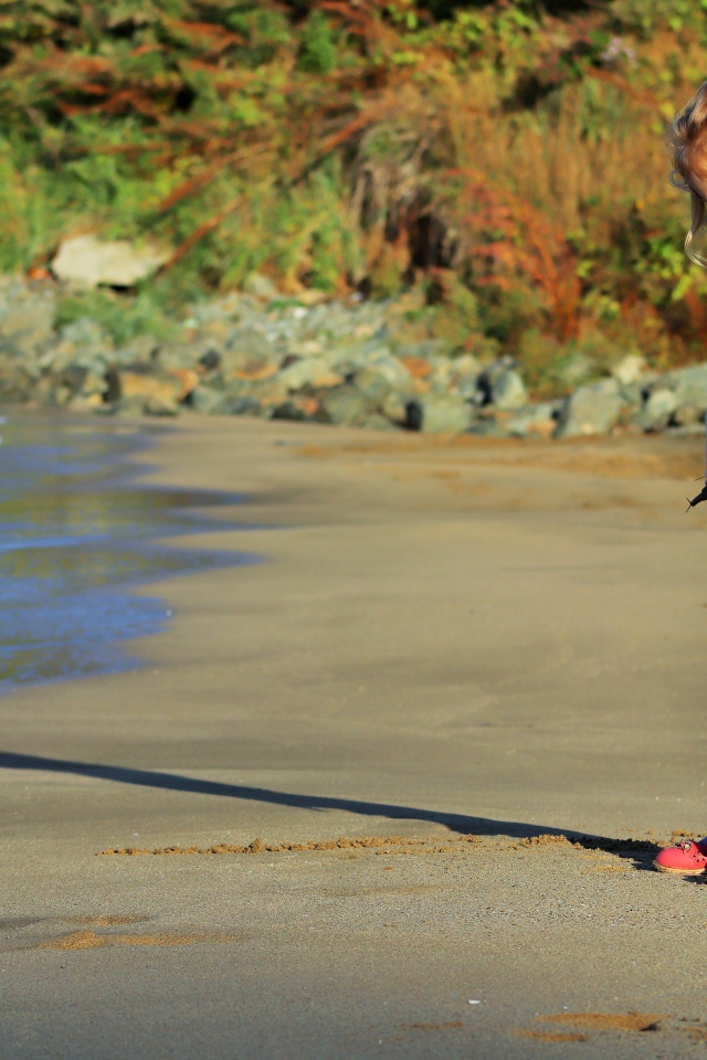 Маленькая девочка гуляет по мокрому песку 