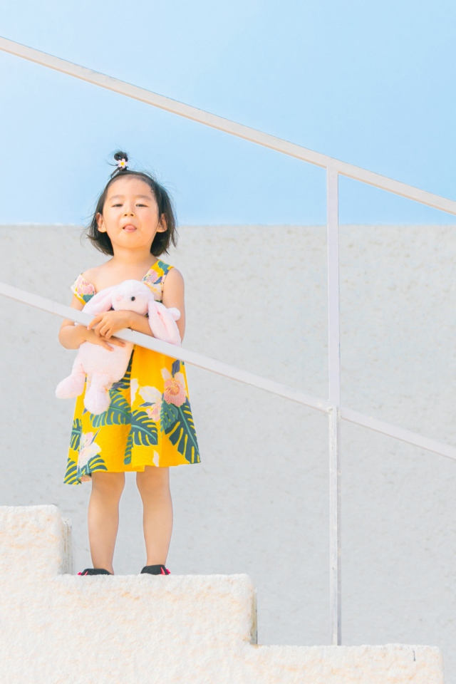 Маленькая девочка с игрушкой на ступеньках 