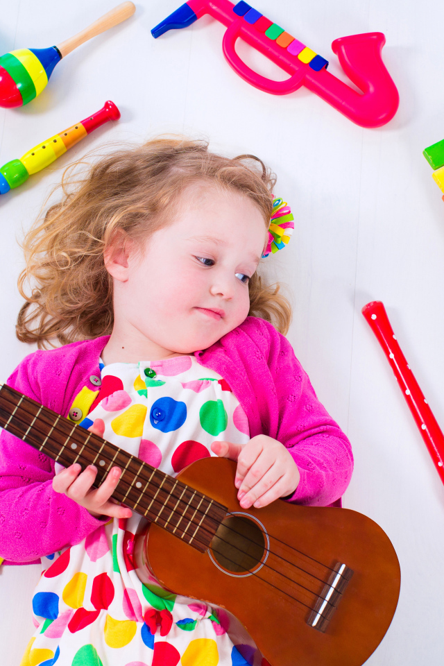 Маленькая девочка с гитарой и игрушечными музыкальными  инструментами 