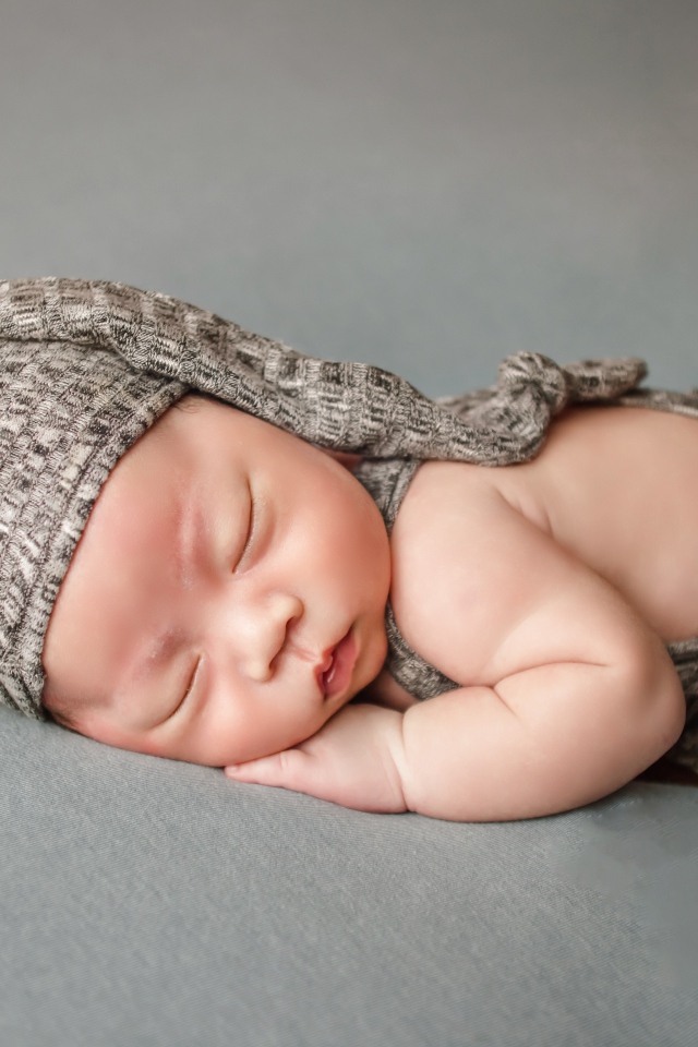 Маленький новорожденный ребенок на сером фоне