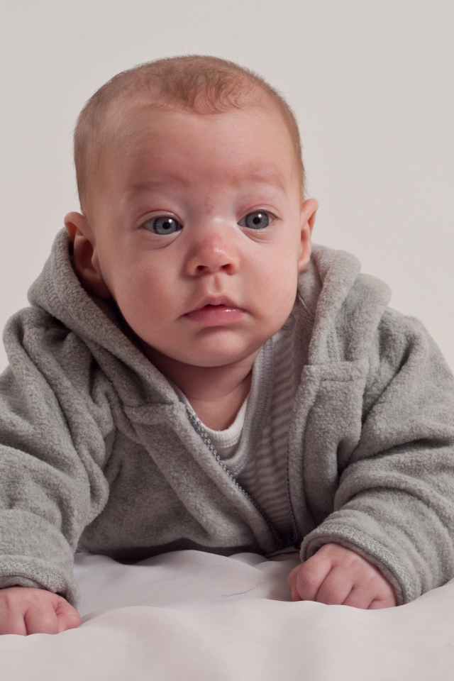 Маленький новорожденный мальчик в сером костюме