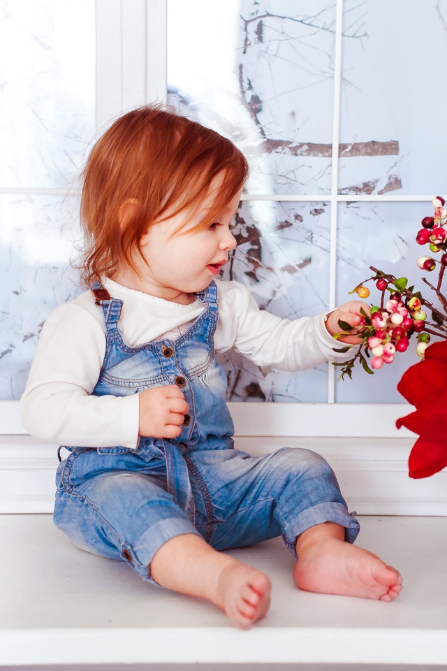 Маленькая рыжеволосая девочка сидит у корзины цветов 