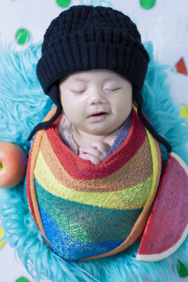 Маленький спящий ребенок в черной шапке 